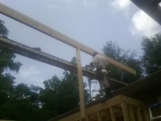 Carpenter setting a ridge beam over a new addition frame — Ice Dam Removal by Roofing Brothers in Ledbetter