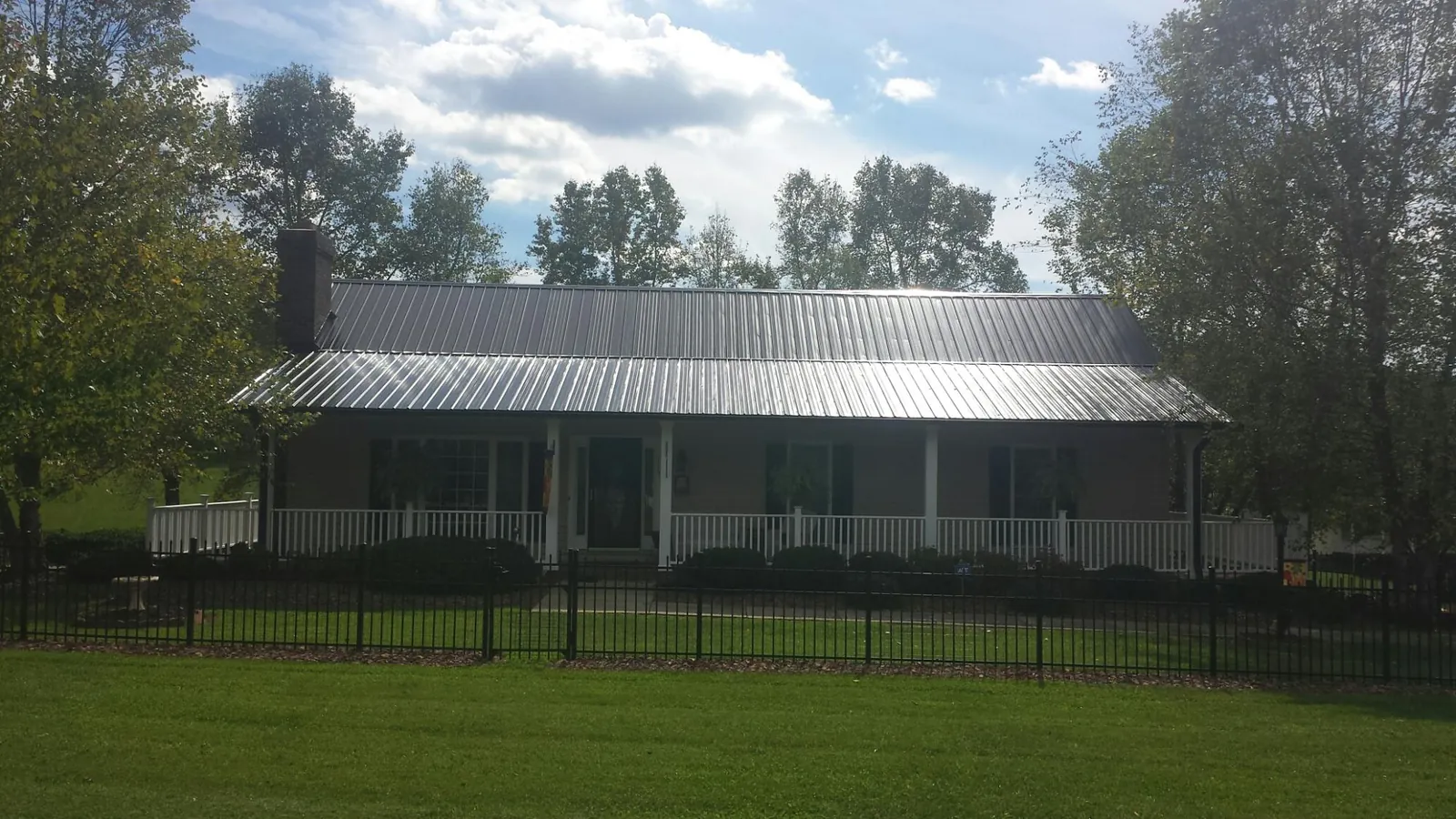 Gray metal roof on a brick ranch with a full width front porch — Gutter Guard Installation work by our crew in Ledbetter