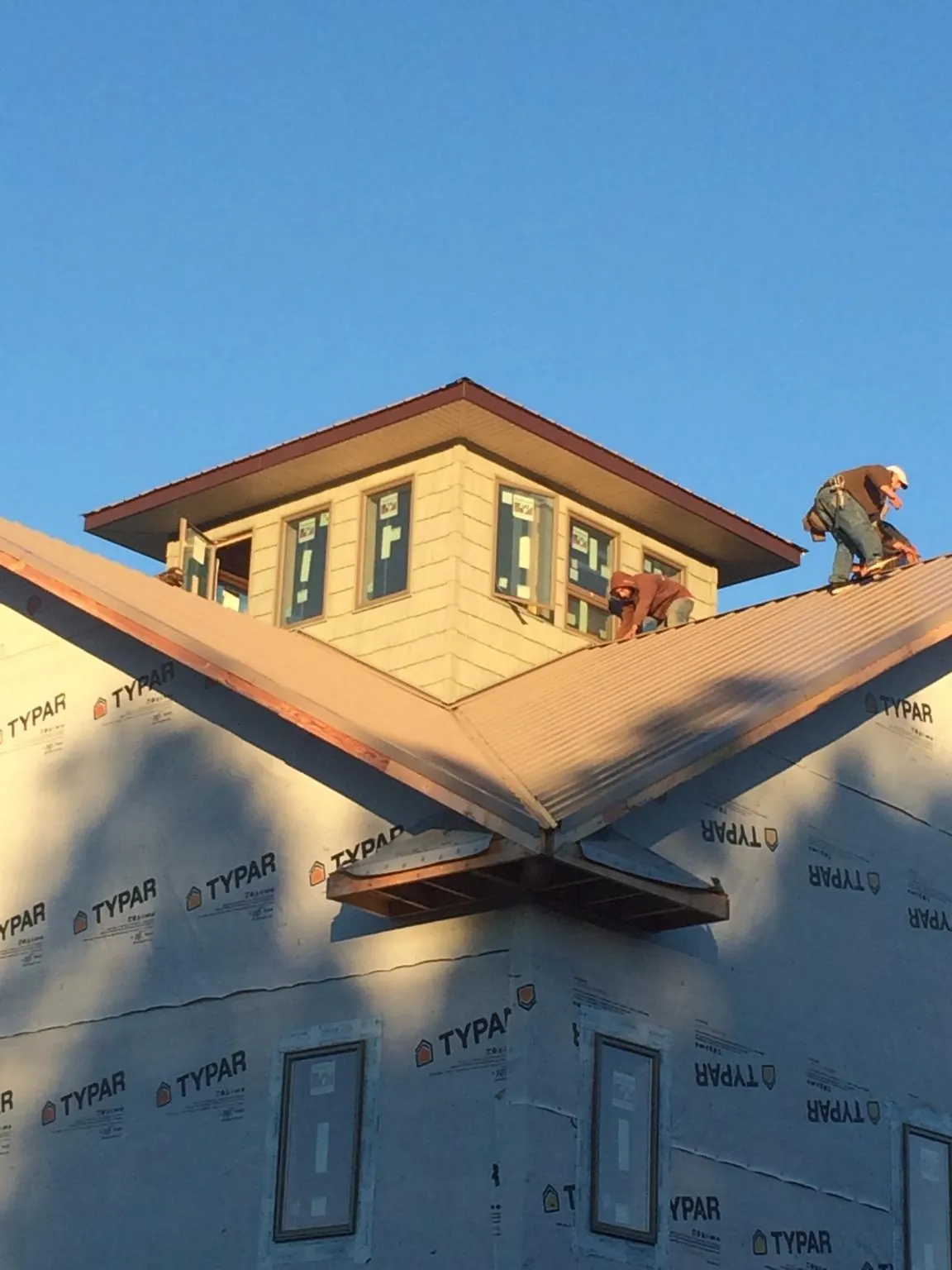 Roofers working around a rooftop cupola on a new metal roof at sunset — Roof Waterproofing in Ledbetter by Roofing Brothers